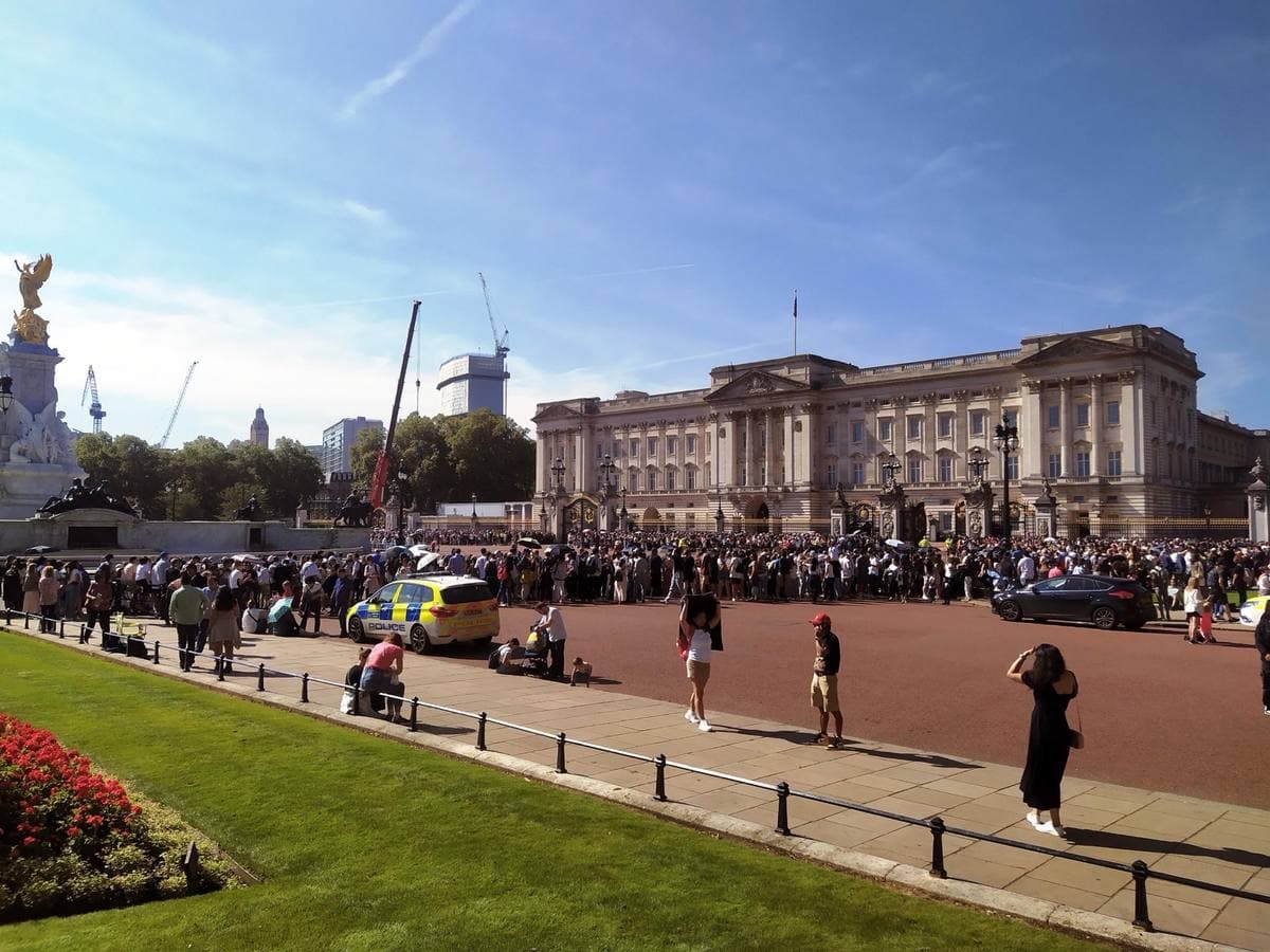 Buckingham Palace across the forecourt with crowds at the railings