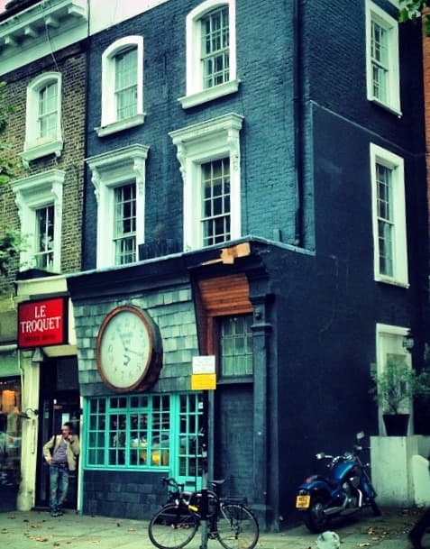 A small dark-blue shop front with a big clock over the door on the King’s Road