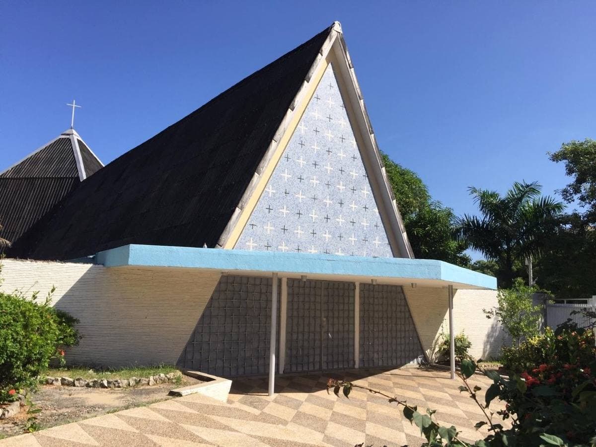 A white school chapel behind palm trees