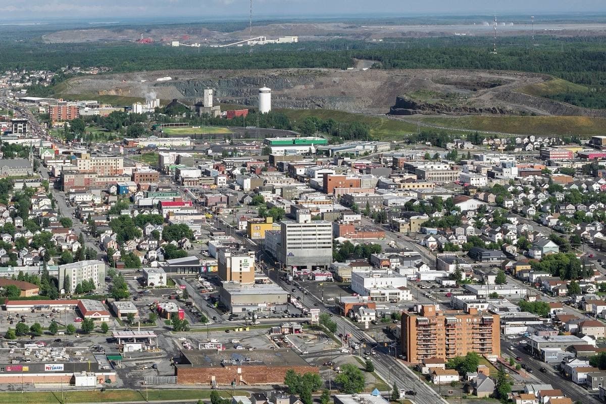 Aerial view of a small northern city with a large open-pit mine behind it