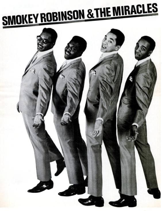 Four men in checked jackets and bow ties standing together, the third from left laughing