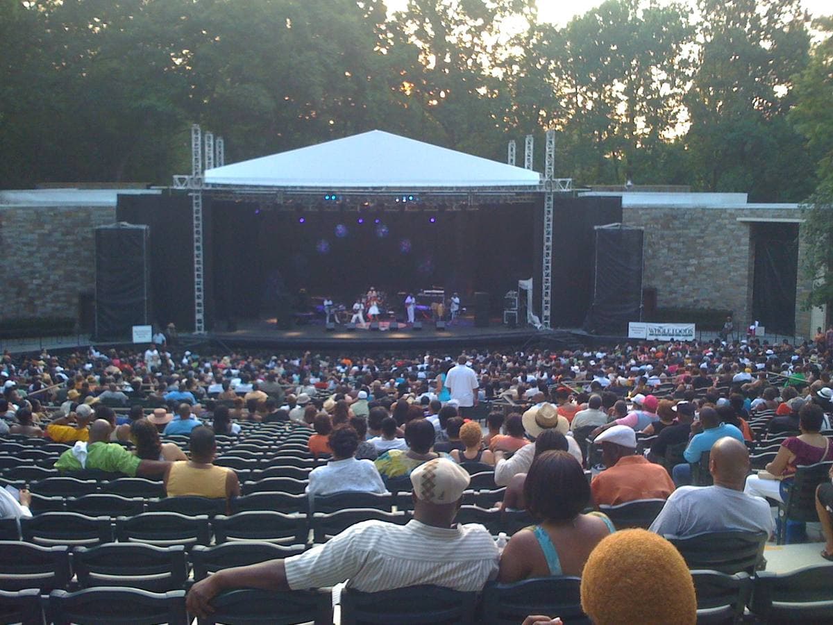 Banks of open-air seats curving down to a stage among trees