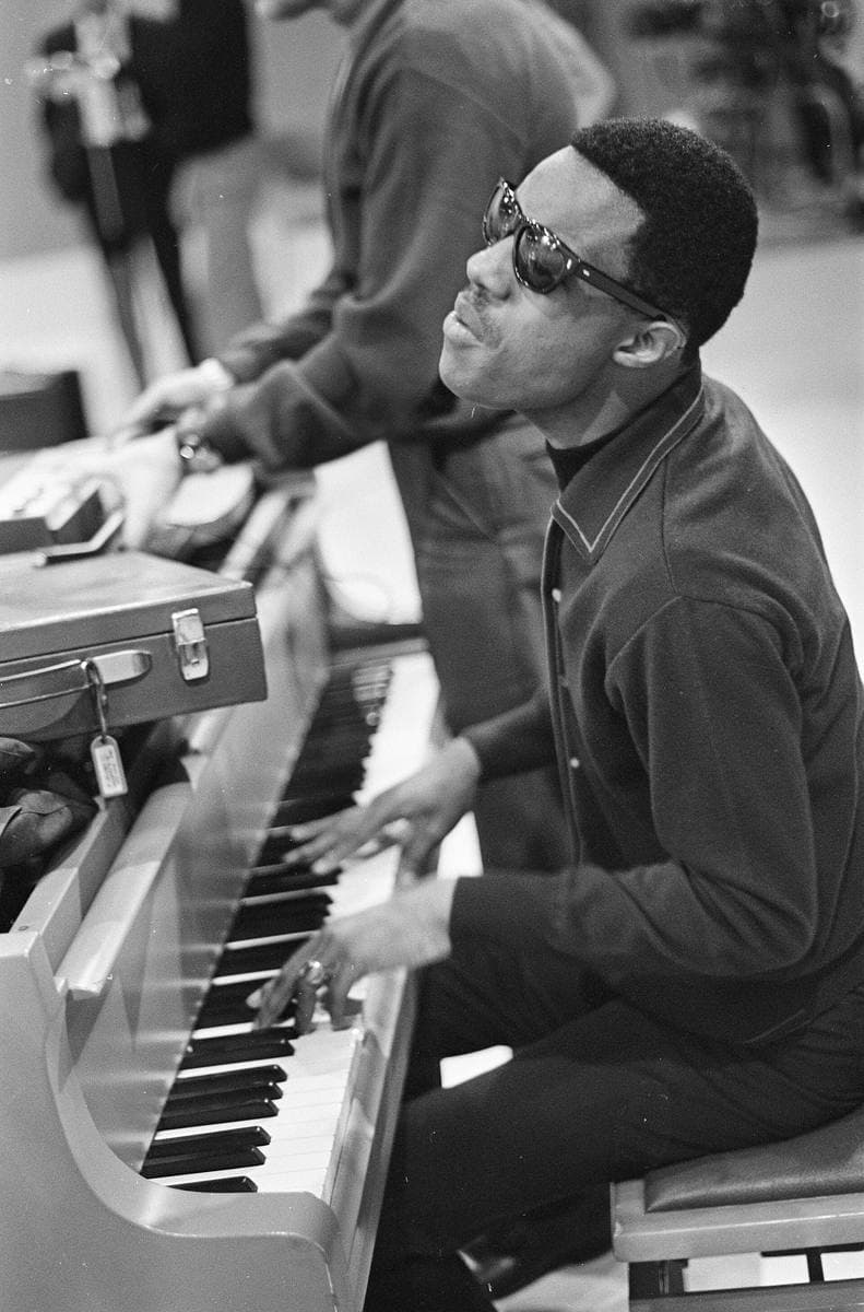 A young Stevie Wonder in dark glasses at a keyboard, smiling