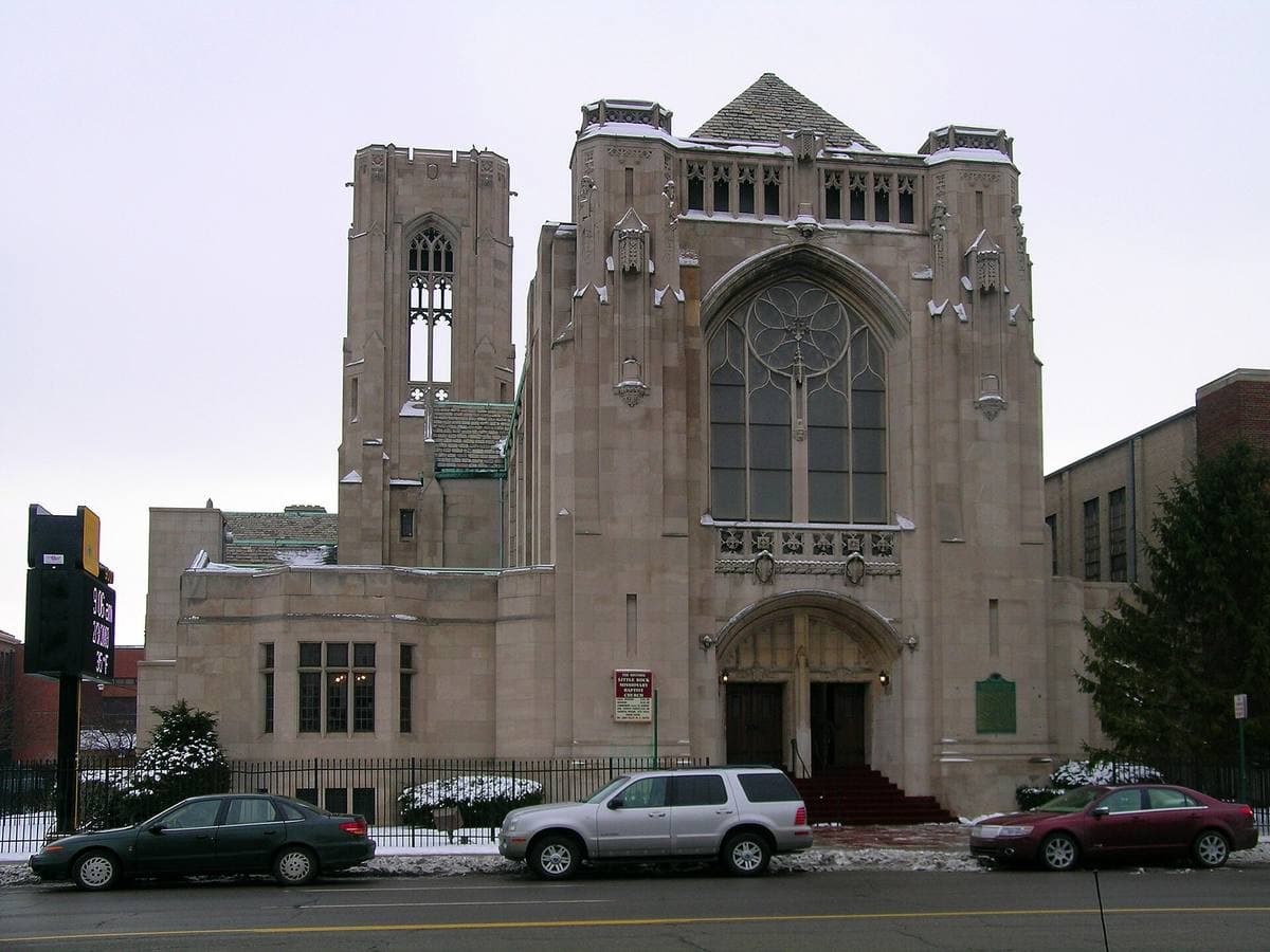 A stone church tower on Woodward Avenue under a pale winter sky
