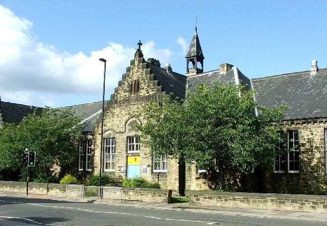 A stone Victorian school building with tall gables and windows