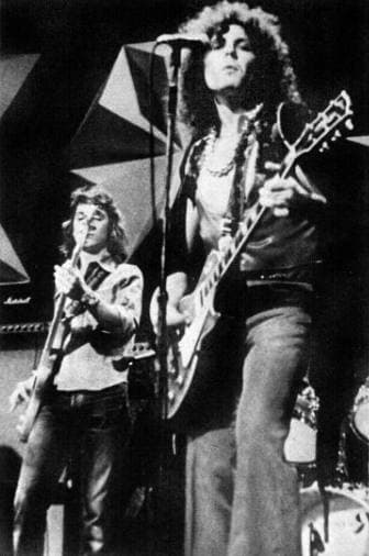 Bolan with a Les Paul at the microphone, Steve Currie on bass behind him