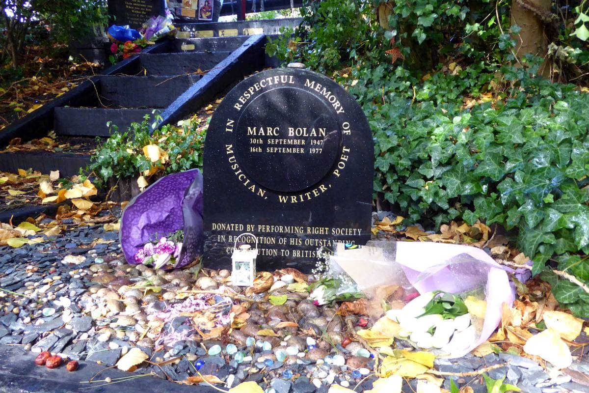A dark memorial stone among plants and flowers