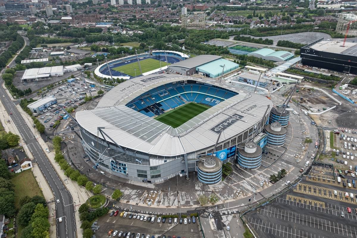 An aerial view of a large oval stadium with its pitch open to the sky