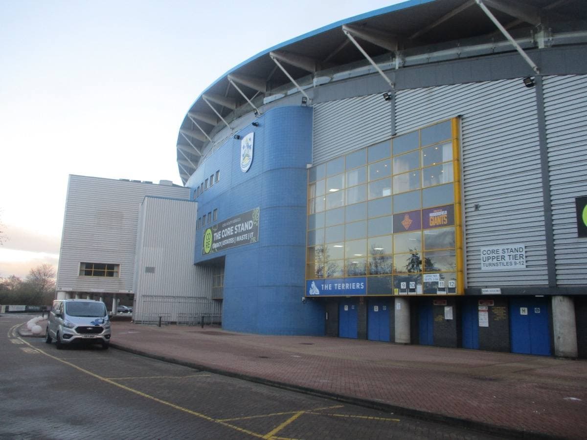 The blue curved side of a modern football stadium with glass stairwells