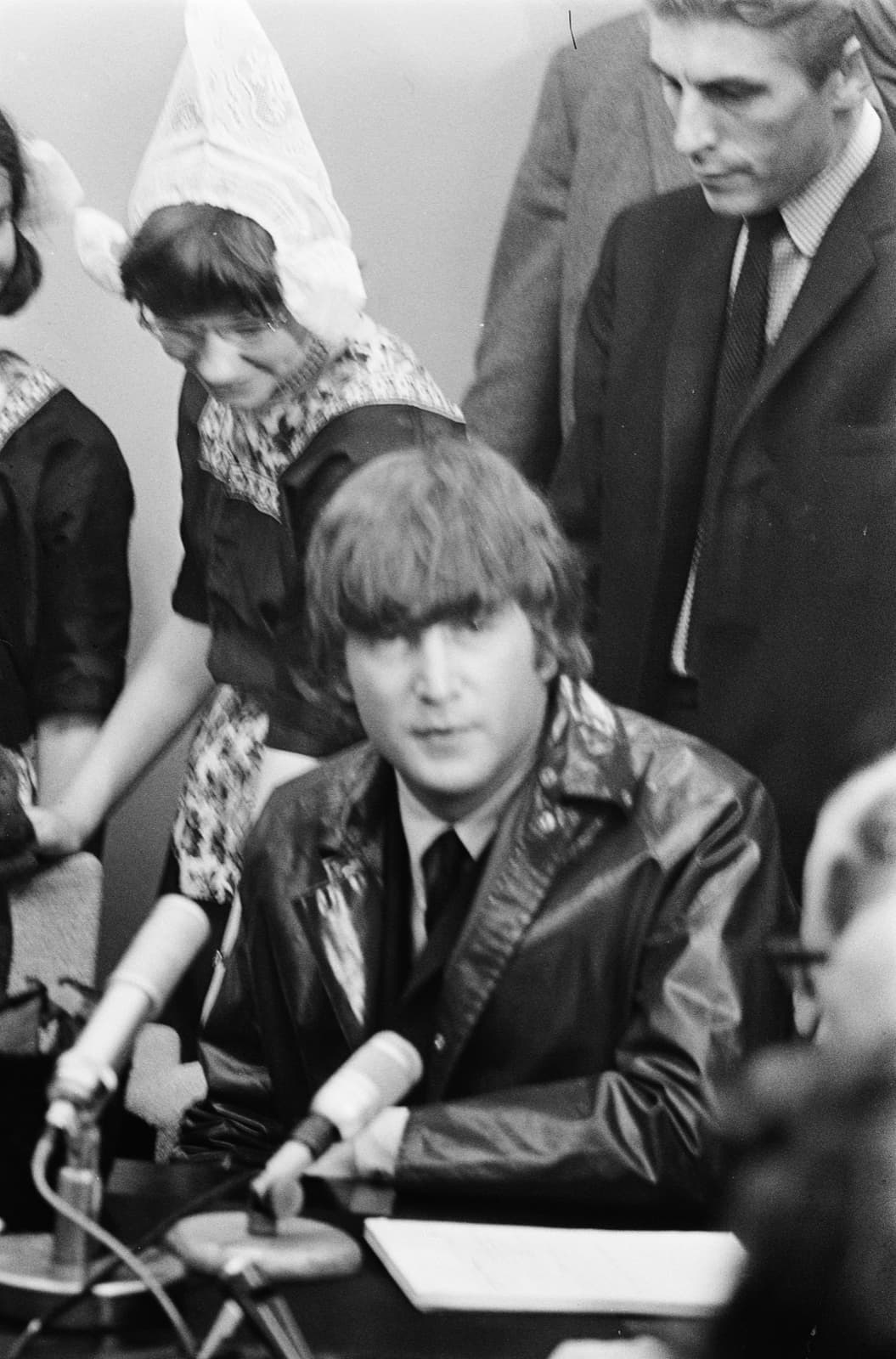 John Lennon at a table of microphones