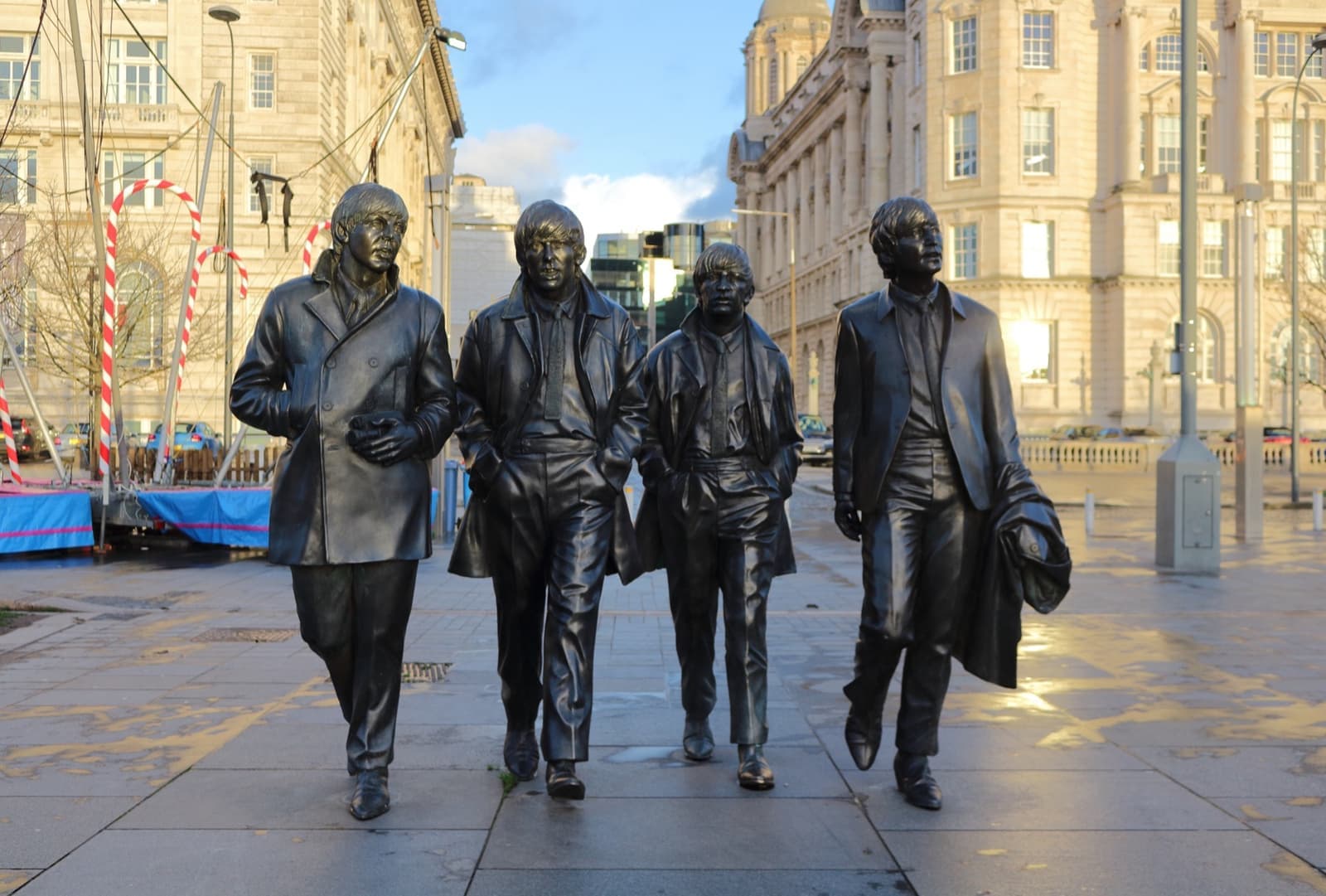 Four larger-than-life bronze figures walking on a waterfront
