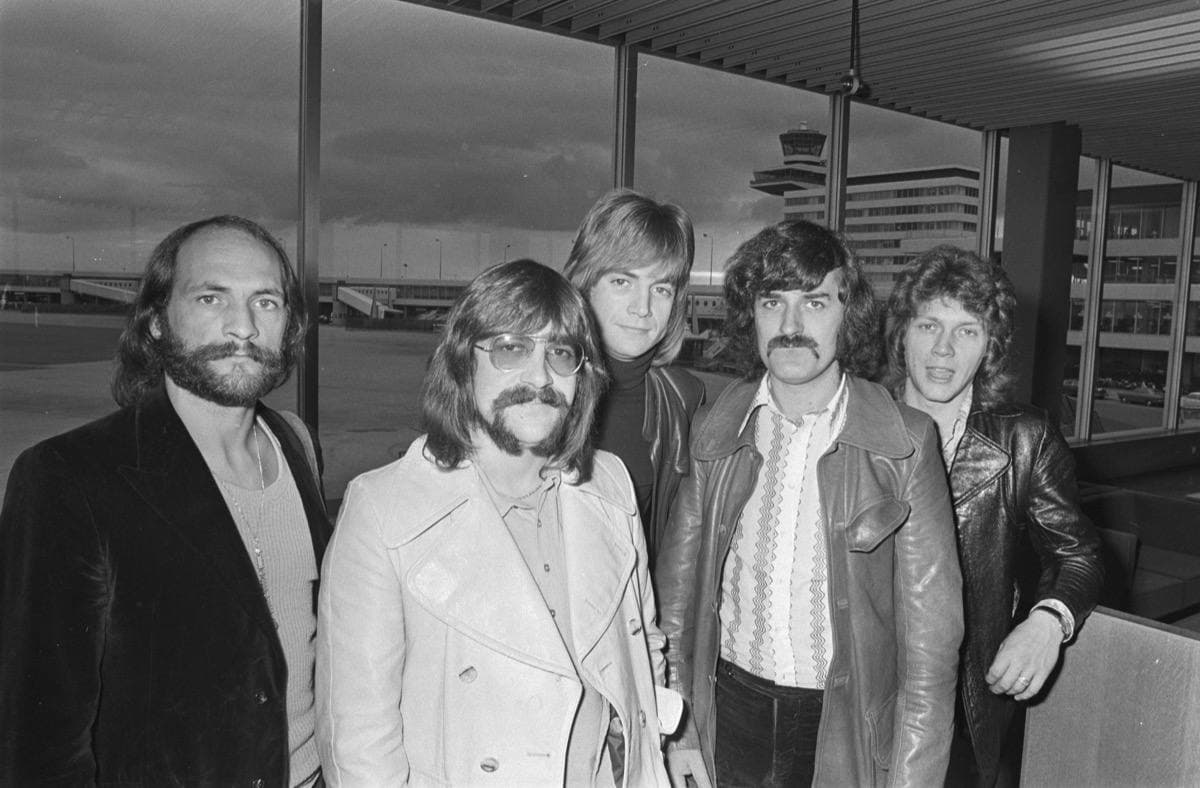 The band walking across an airport apron in October 1970, in black and white