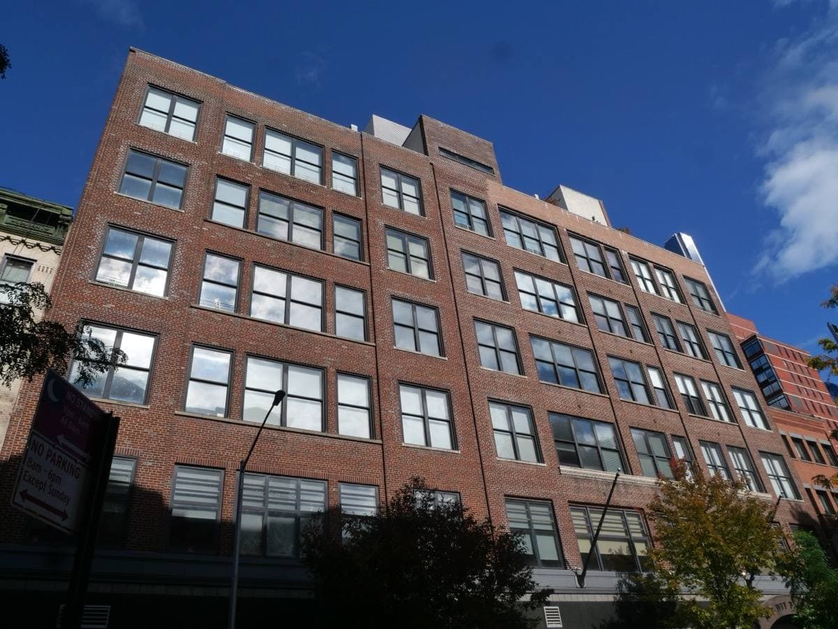 A tall red-brick former studio building on West 54th Street under a blue sky