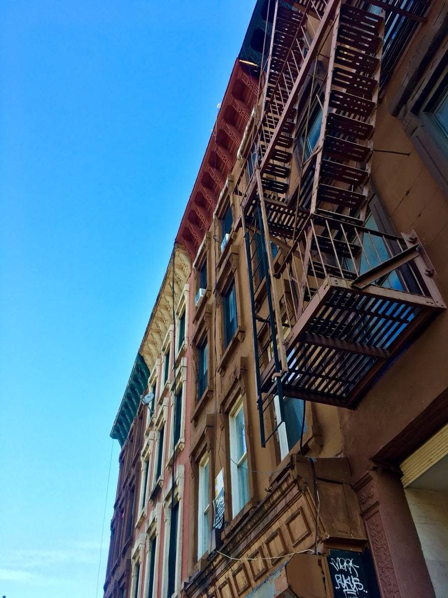 Brick row houses with painted fronts and fire escapes seen from below
