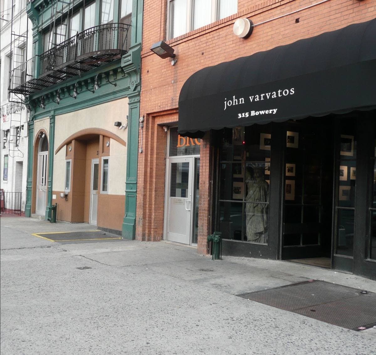 A shopfront with a black awning on a pale building on the Bowery