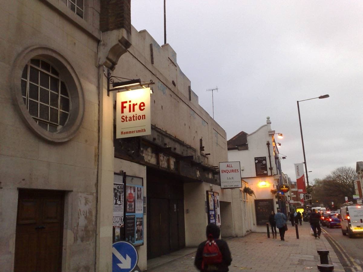 A shabby two-storey club front with boarded doors on a London street