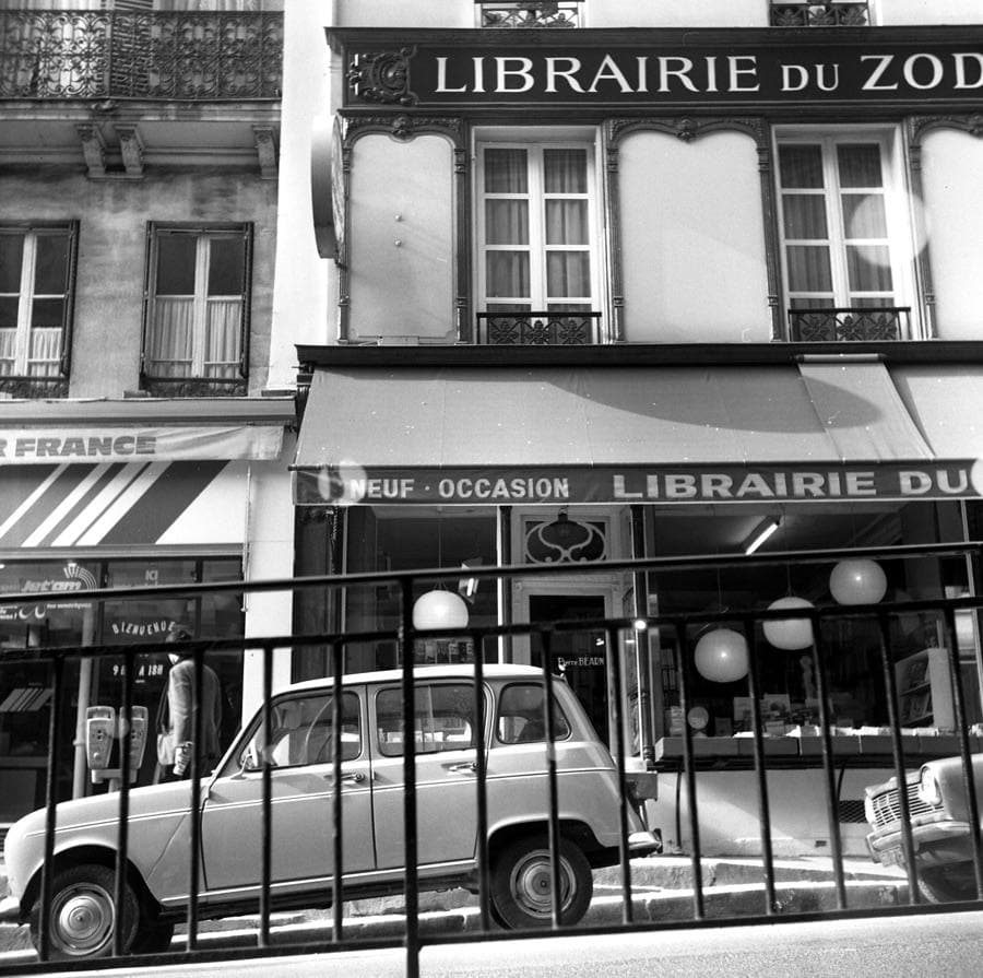 A narrow Paris street of tall old buildings in black and white
