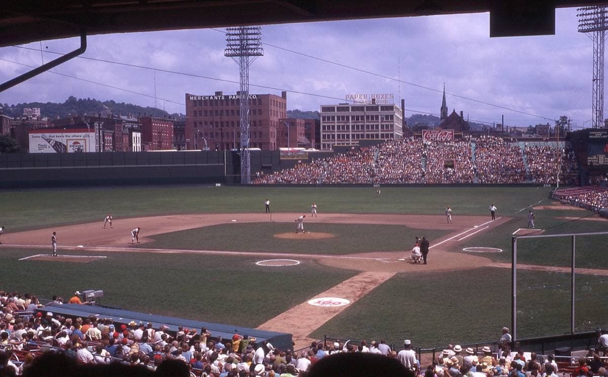 An old ballpark grandstand and green field in summer