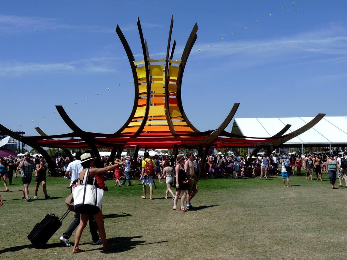 A festival stage and crowd on polo-field grass in desert sun