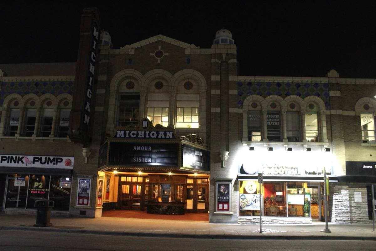 A lit vertical sign and marquee on a theatre front at night