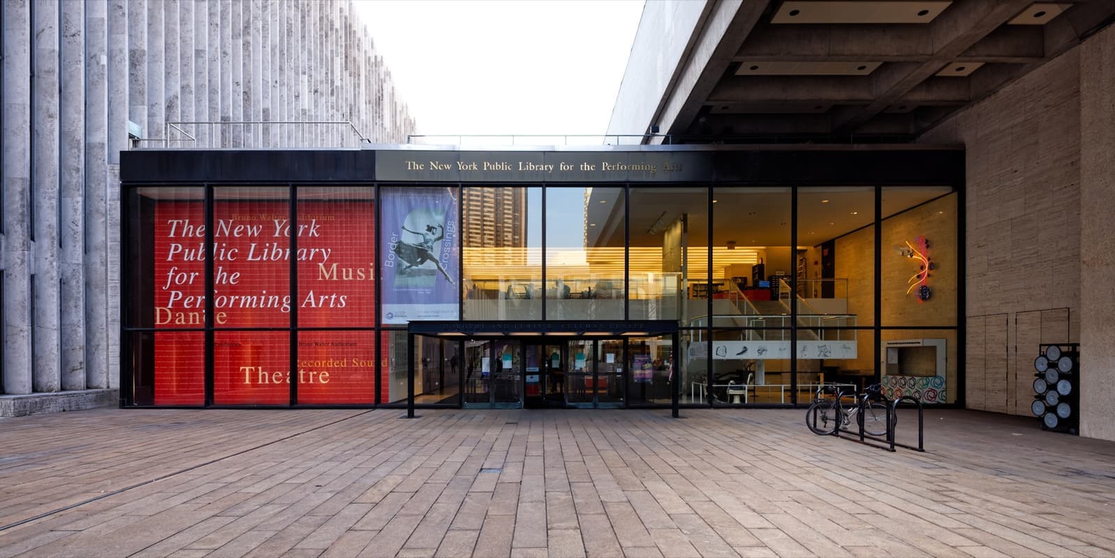 A wide glass-fronted library entrance on a Lincoln Center plaza