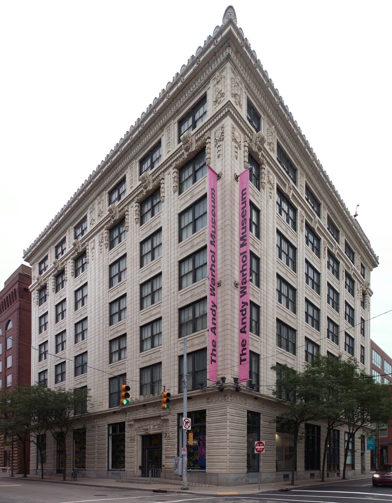 A tall brick and terracotta warehouse building with a large vertical WARHOL banner