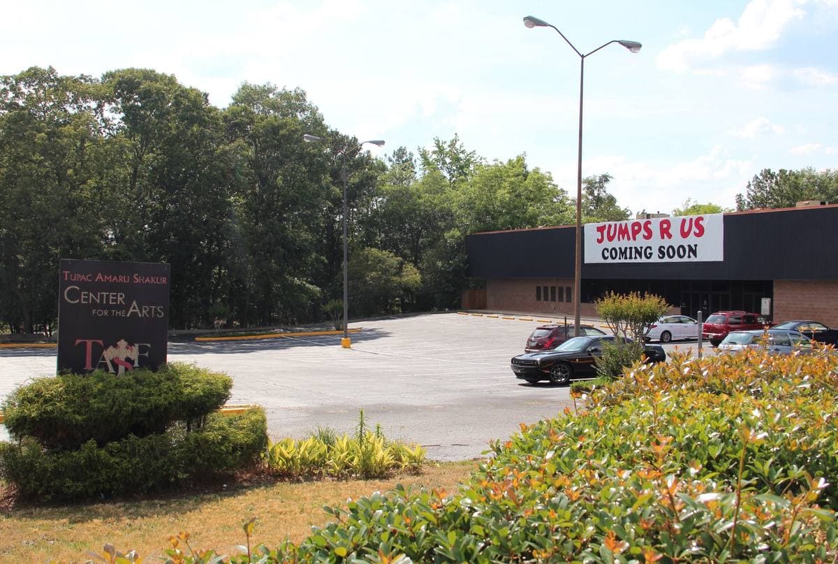 The Tupac Amaru Shakur Center for the Arts sign by a car park off Memorial Drive, with a shop building behind