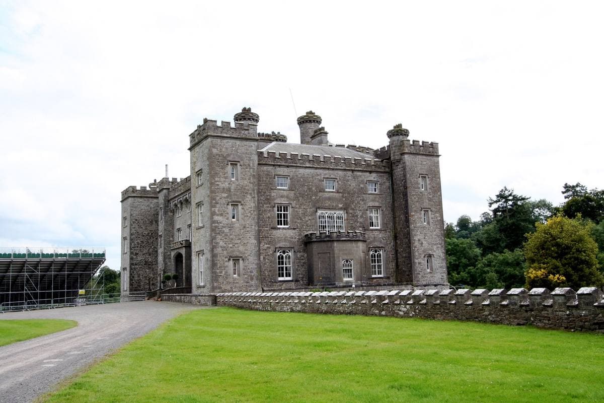 A grey castellated house on a lawn under a pale sky
