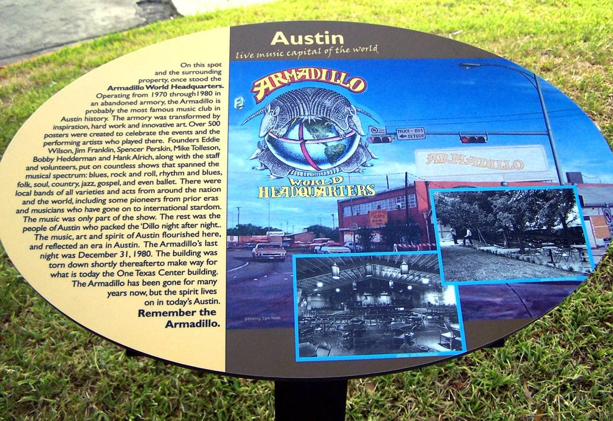 A bronze plaque with an armadillo on it, set on a stone in a car park