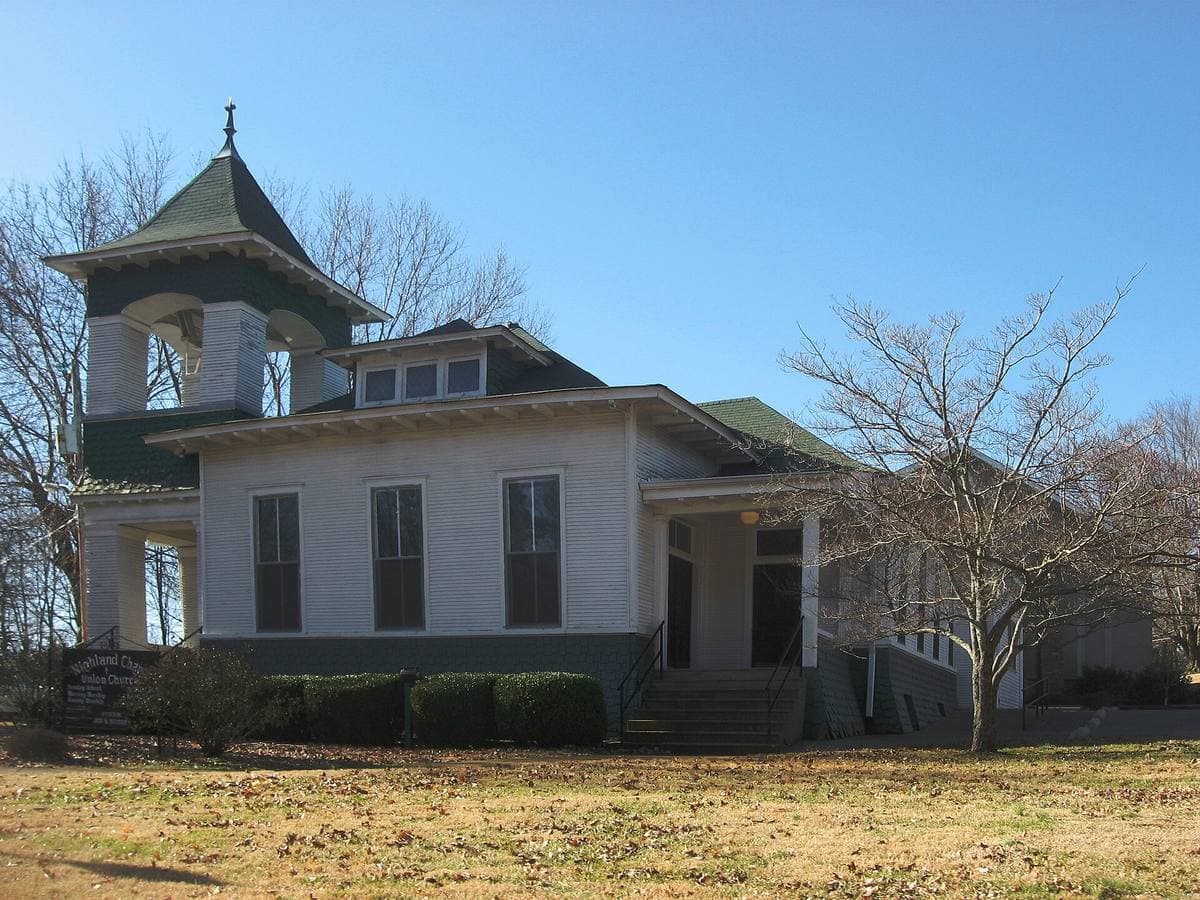 A small white clapboard chapel with a short spire on a winter lawn