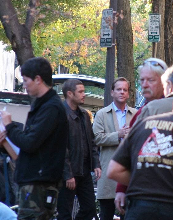 Two actors on a Georgetown street during filming, seen from a distance