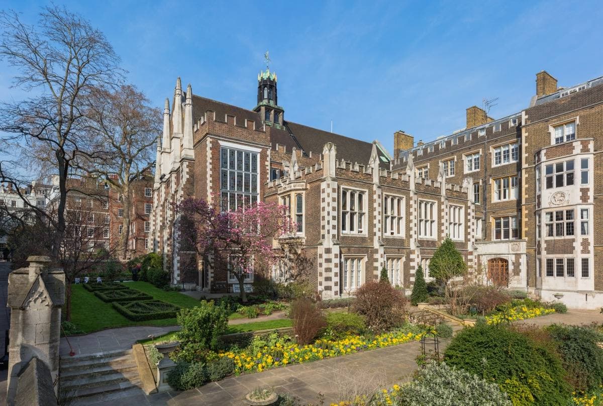 A Tudor hall of red brick and stone beside a lawn