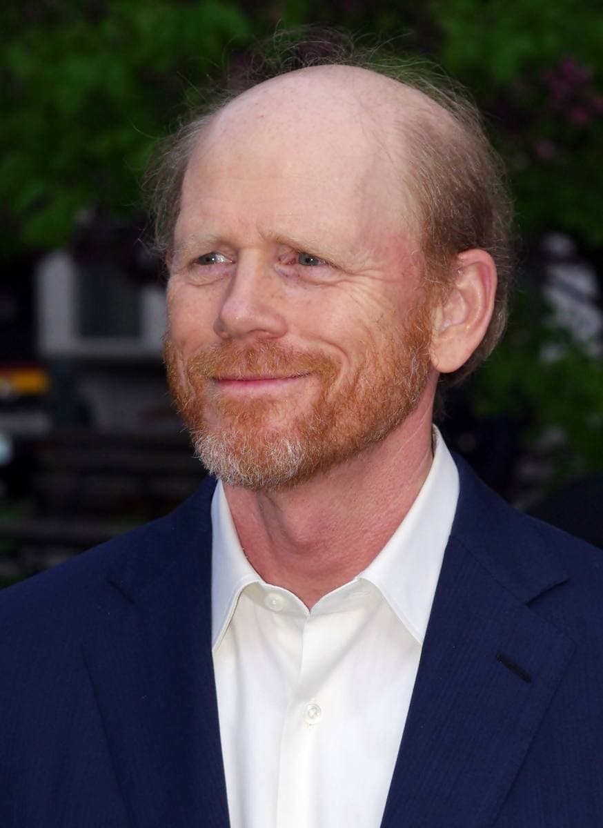Ron Howard in a dark jacket and cap, smiling