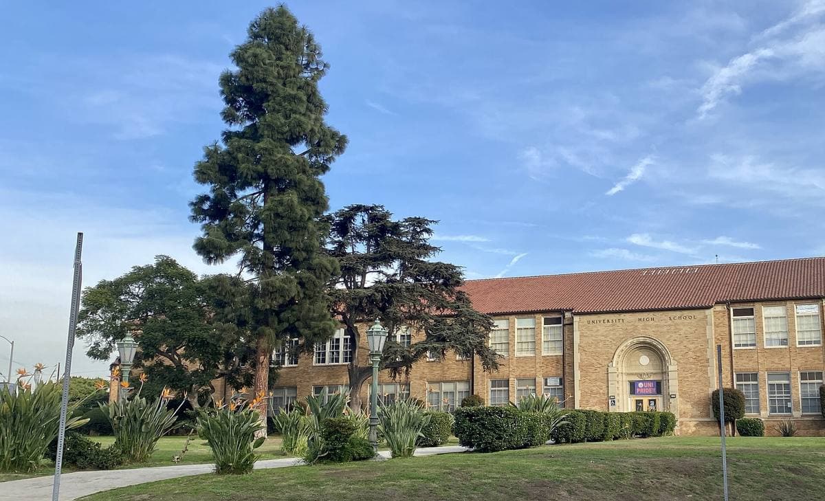Brick school buildings behind trees on Texas Avenue