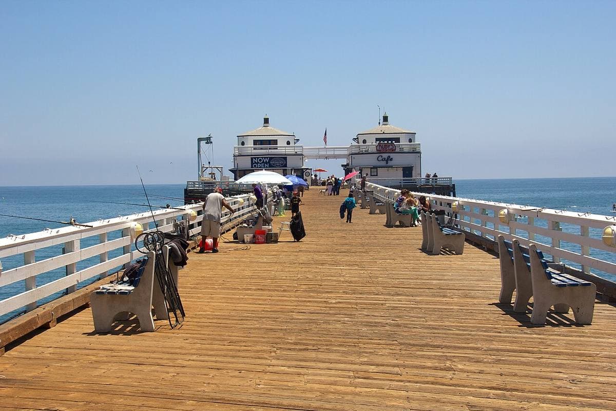 A long wooden pier running out to sea from a beach