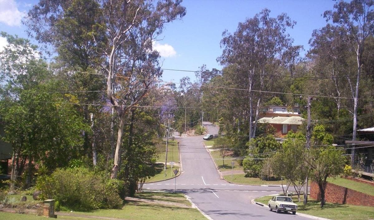 Quiet suburban street with trees and houses set back from the road
