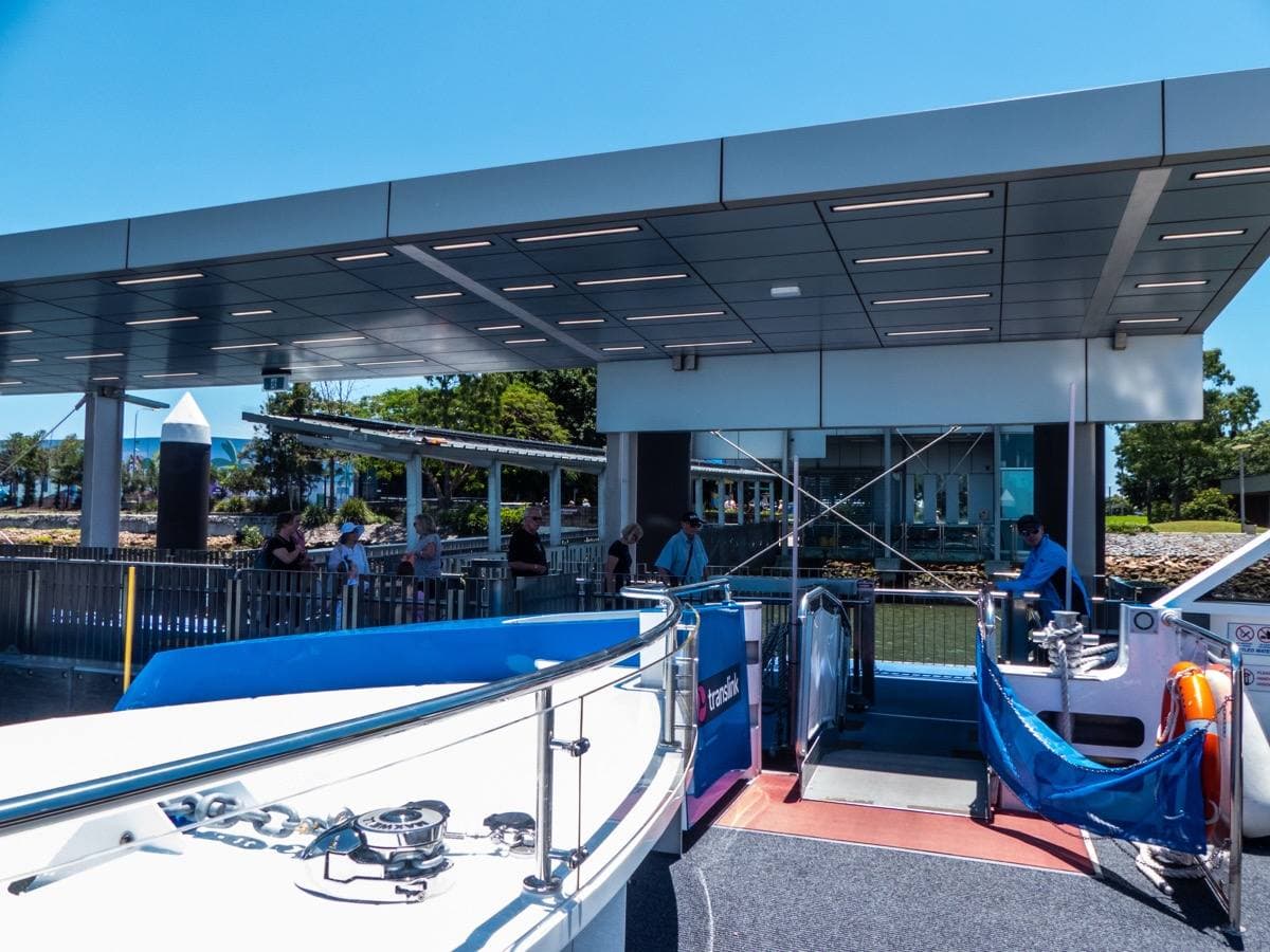 Blue and white river ferry lowering its gangplank at a riverside pontoon