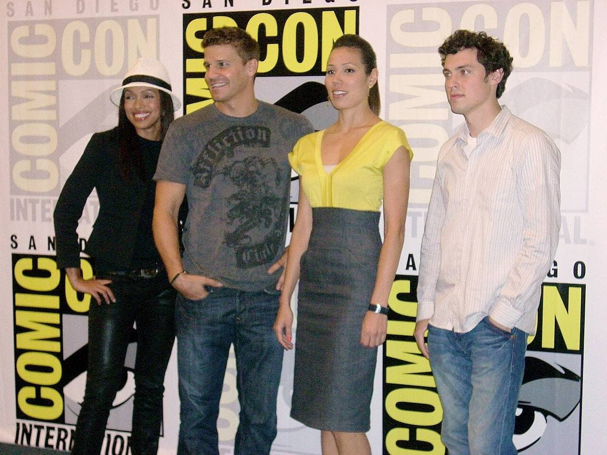 Four members of the cast seated at a convention panel table