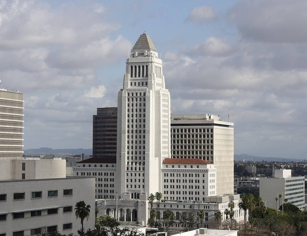 A tall white stepped tower above downtown buildings