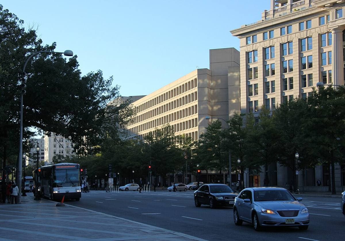 A massive concrete office building across a wide avenue