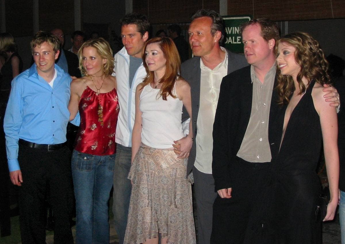 Seven people from the Buffy cast and crew standing together and smiling at a party