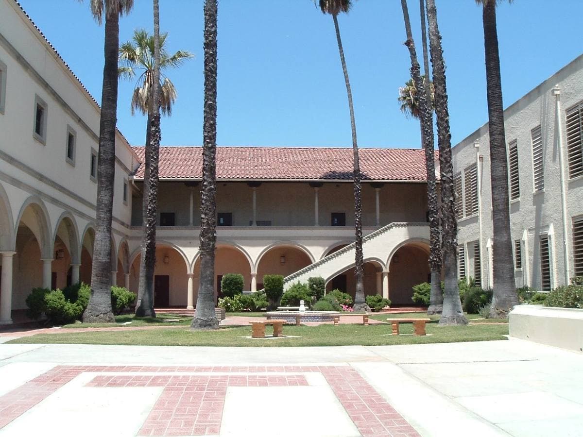 A school courtyard with arches, palm trees and a paved patio