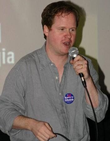 Joss Whedon speaking, in glasses and a dark shirt