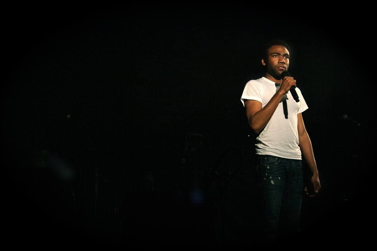 A young man performing on a stage under coloured lights