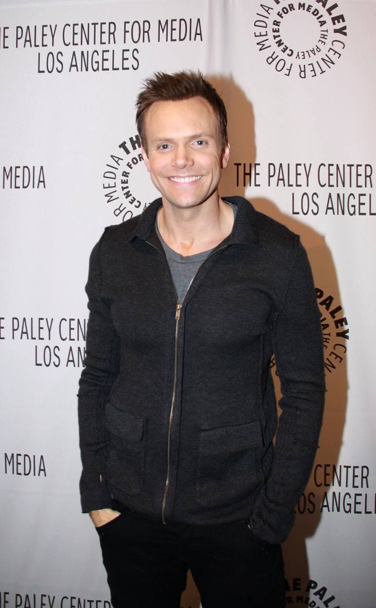 A smiling man in a dark jacket at a public event