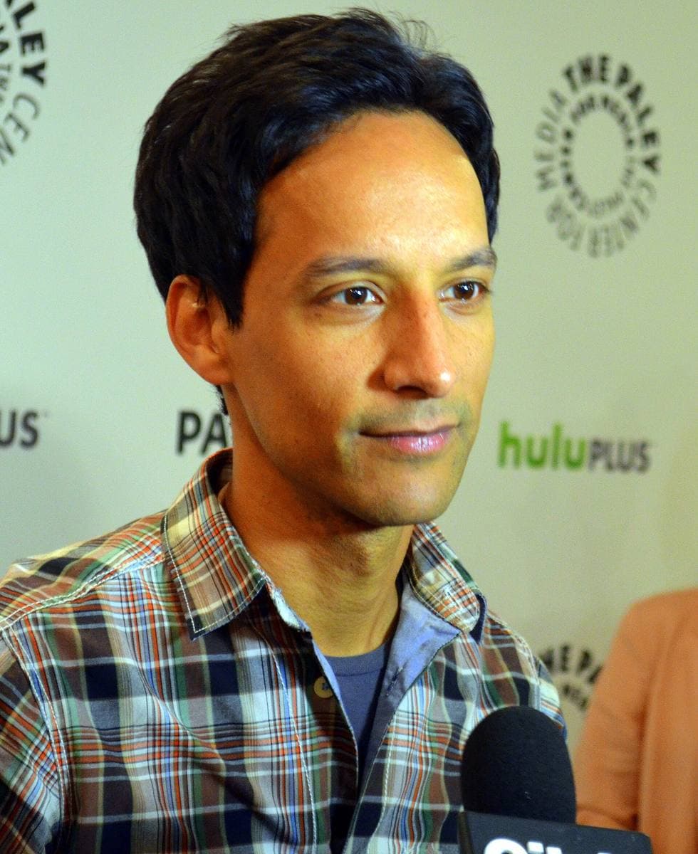 A smiling man in a suit at a press backdrop