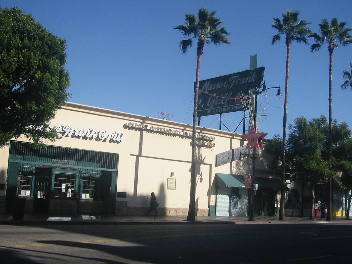 The low cream frontage of Musso & Frank Grill with its sign and palms
