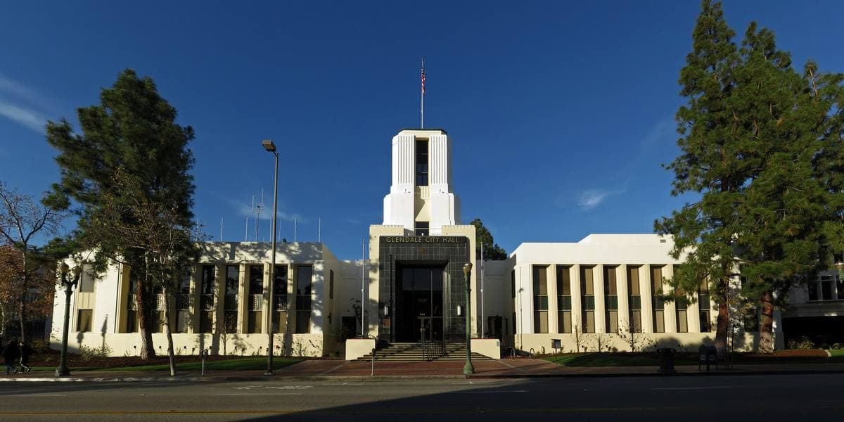 A long Spanish-style civic building with a tower behind lawns