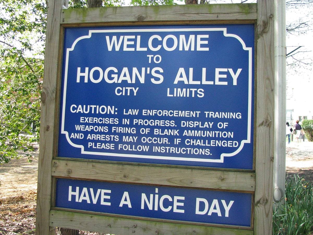 A sign reading Hogan’s Alley beside a road among trees