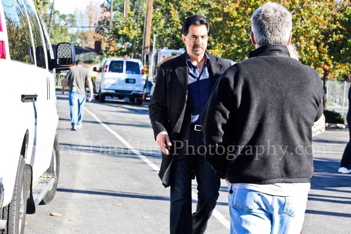 A grey-bearded man in a dark coat on a location shoot